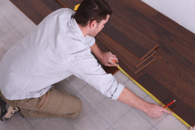 man measuring tile flooring for installation
